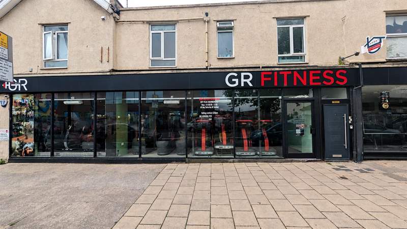 The GR Fitness shopfront on Gloucester Road: black fascia, red lettering, vibration plates in the window.