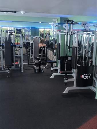 Pin-loaded resistance machines and a GR-branded cable stack against the green wall.